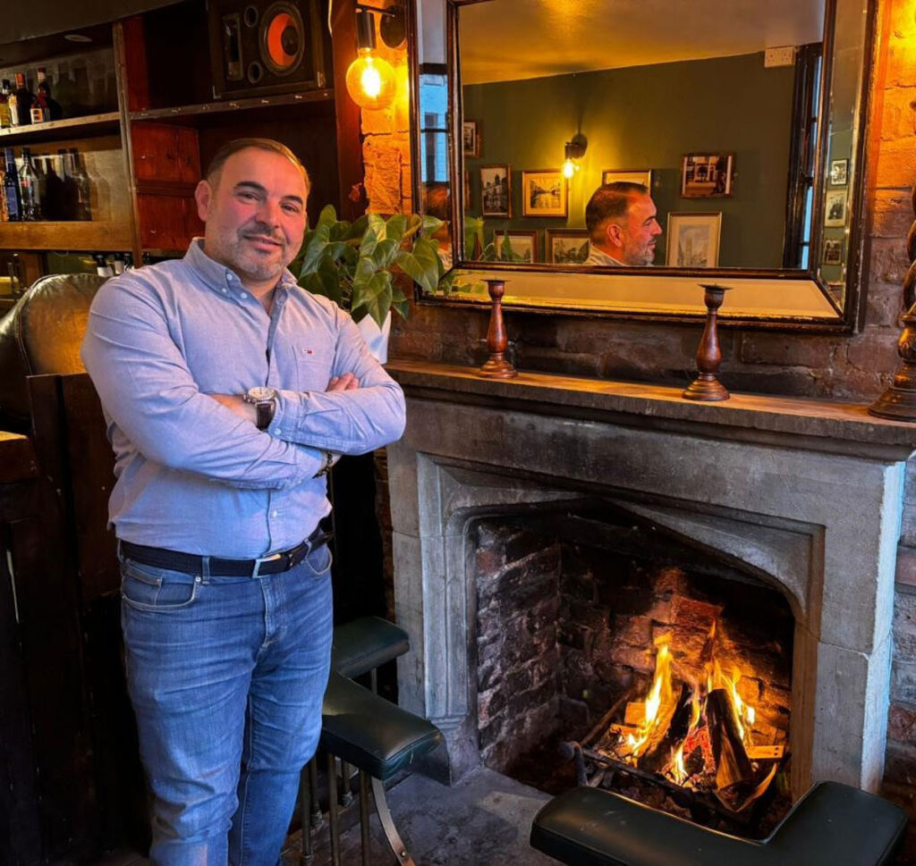 A guest beside the fireplace at The Plough Inn